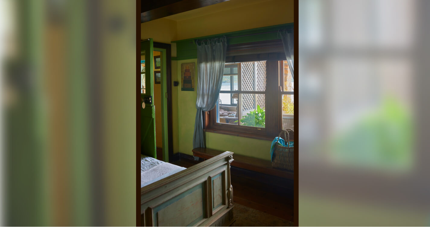 The view from the Seagulls Nest bedroom. Beyond the window are plants. Beyond the window is a balcony full of plants.