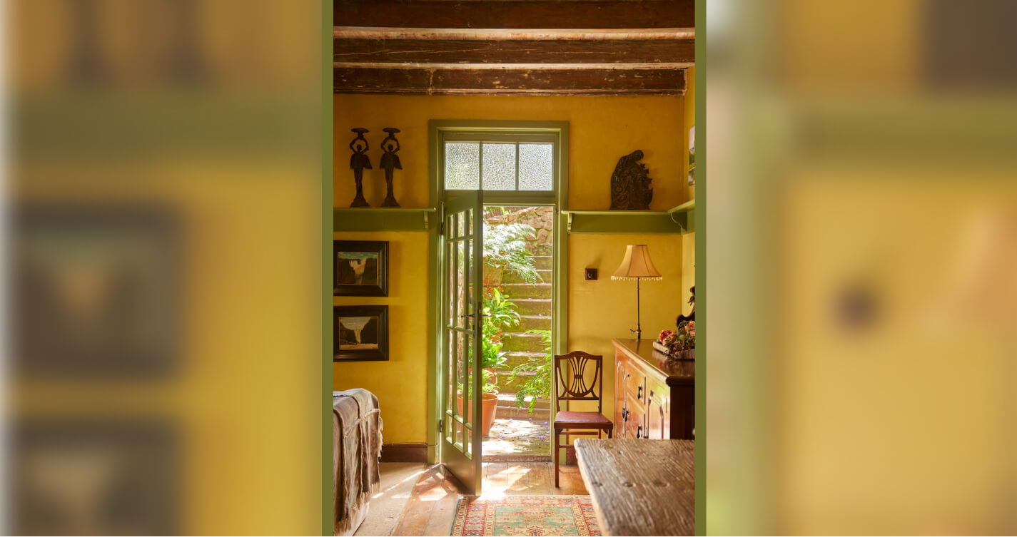 The back entrance to the TwoAngels Luxury Suite. Light spills into the suite through the open green-olive coloured door.