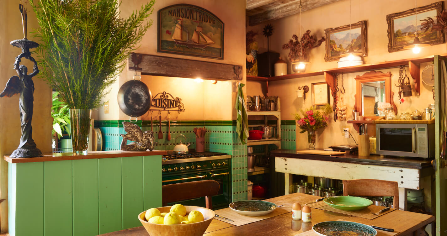 The beautiful, fully equipped Luxury Suite kitchen. It has a gas stove and dining table. The stove is olive green with brass finishes.